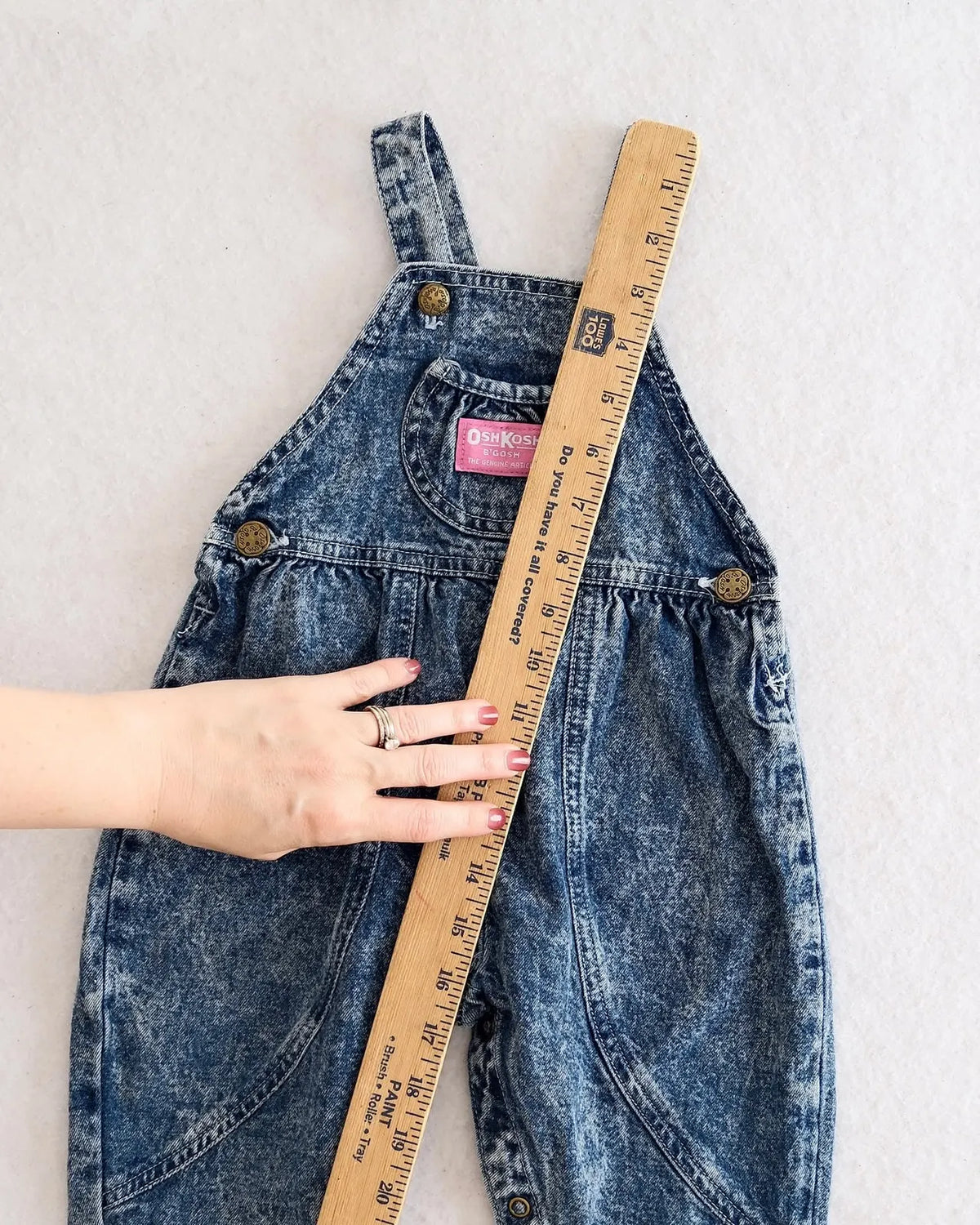 Vintage OshKosh B'gosh blue acid wash overalls with pink label and embossed OshKosh girl on back