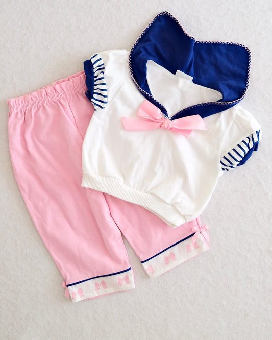 Vintage Carter's girls pink navy sailor three-piece set, front flat lay, white sailor top with navy striped ruffle sleeves and pink satin bow, pink pants with bow-print cuffs and ribbon trim, navy felt bib, Made in USA