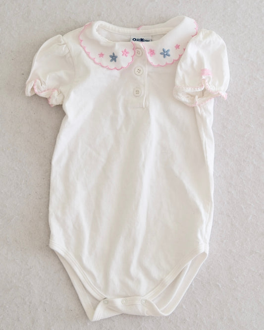 Vintage OshKosh B'Gosh girls white puff sleeve bodysuit size 24 months, front flat lay, scalloped Peter Pan collar with pink and blue embroidered flowers, pink scallop and lace trim at sleeve