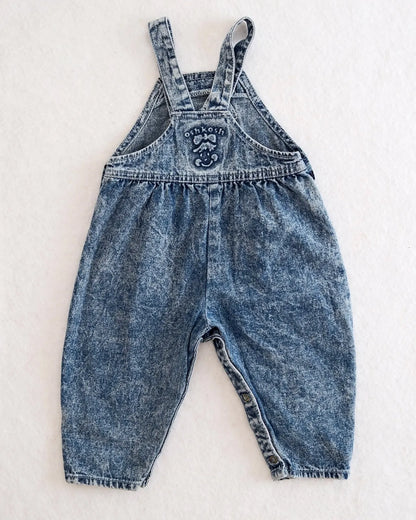 Vintage OshKosh B'gosh blue acid wash overalls with pink label and embossed OshKosh girl on back