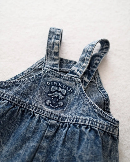 Vintage OshKosh B'gosh blue acid wash overalls with pink label and embossed OshKosh girl on back
