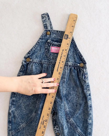 Vintage OshKosh B'gosh blue acid wash overalls with pink label and embossed OshKosh girl on back